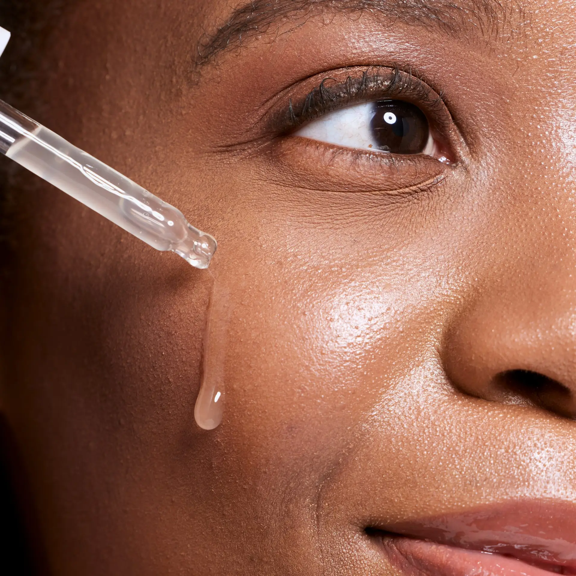 Close-up of facial serum dropper on glowing skin